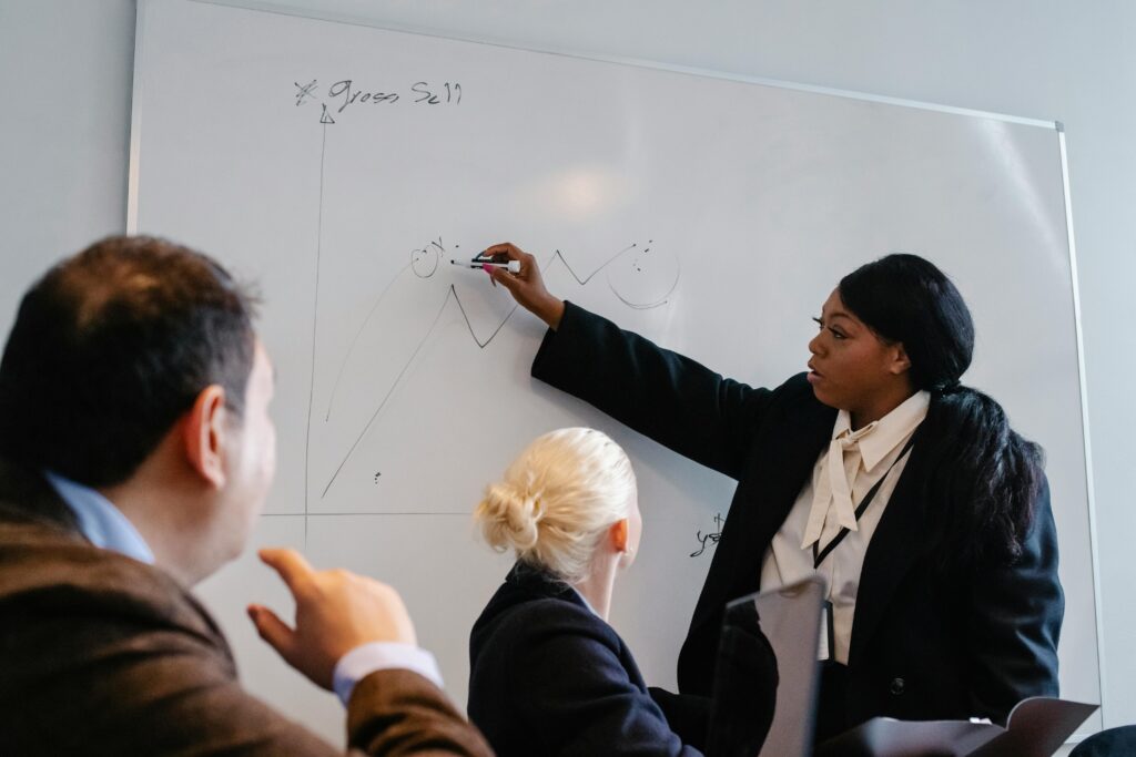 Group of multiethnic coworkers in formal wear discussing business plan and analyzing diagrams in team